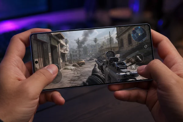 First-person view of a gamer holding a Galaxy S26 Ultra in landscape mode while playing a Call of Duty-style mobile shooter under purple gaming lights.